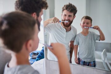 Shot of a father and his little son brushing their teeth together in the bathroom at home.