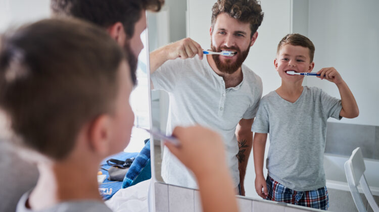 Shot of a father and his little son brushing their teeth together in the bathroom at home.
