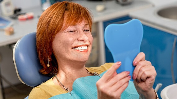 A woman smiling siting on the chair and looking at the camera